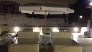 An outdoor seating area with two lounge chairs and a table under a canopy. - Alkyonis Apartments (Kalymnos)