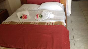 A neatly made bed with a red blanket, two white pillows, and a red headboard.