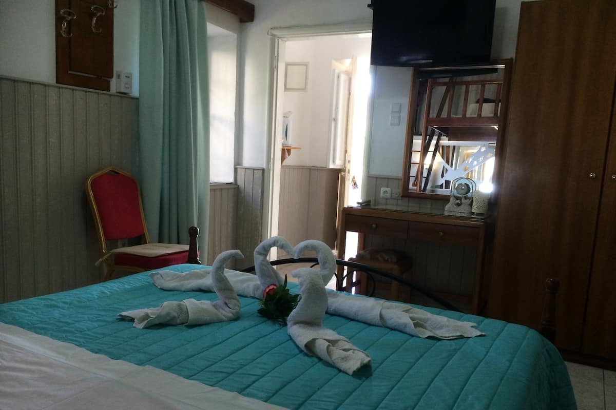 A hotel room with a bed, a desk, a chair, and a wardrobe.