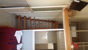 A room with a bed, a wooden ladder, a white wall, and a window. - Alkyonis Apartments (Kalymnos)