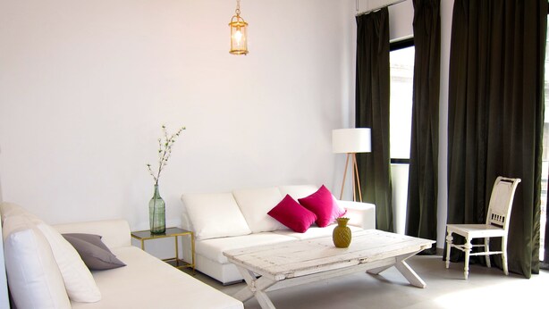 A modern living room with a white sofa, a coffee table, a lamp, and a chair. - Concierge Monastiraki (Athens)