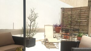 An outdoor patio with wicker furniture, a table, and potted plants. - Concierge Monastiraki (Athens)