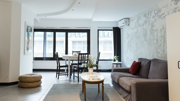 Una sala de estar moderna con sofá, una mesa de centro y un comedor con sillas y una mesa.