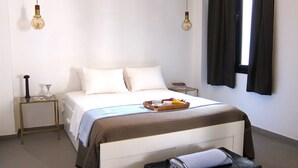 Una habitación de hotel con cama, mesitas de noche, una maleta y una ventana con cortinas.
