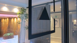Un interior moderno con un vidrio, una planta en maceta y una pared de madera.