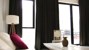 Una habitación con un sofá blanco, una mesa de madera, una lámpara de pie y vistas amplias a través de grandes ventanales.