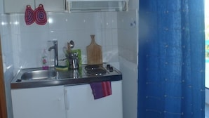 A compact kitchen with a sink, stove, and white cabinets. - SeaShell Apartments (Platanias)