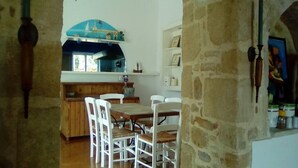 A rustic kitchen with a wooden table and chairs, a blue archway, and stone walls. - SeaShell Apartments (Platanias)