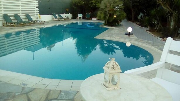 A swimming pool with lounge chairs and a decorative lantern. - SeaShell Apartments (Platanias)