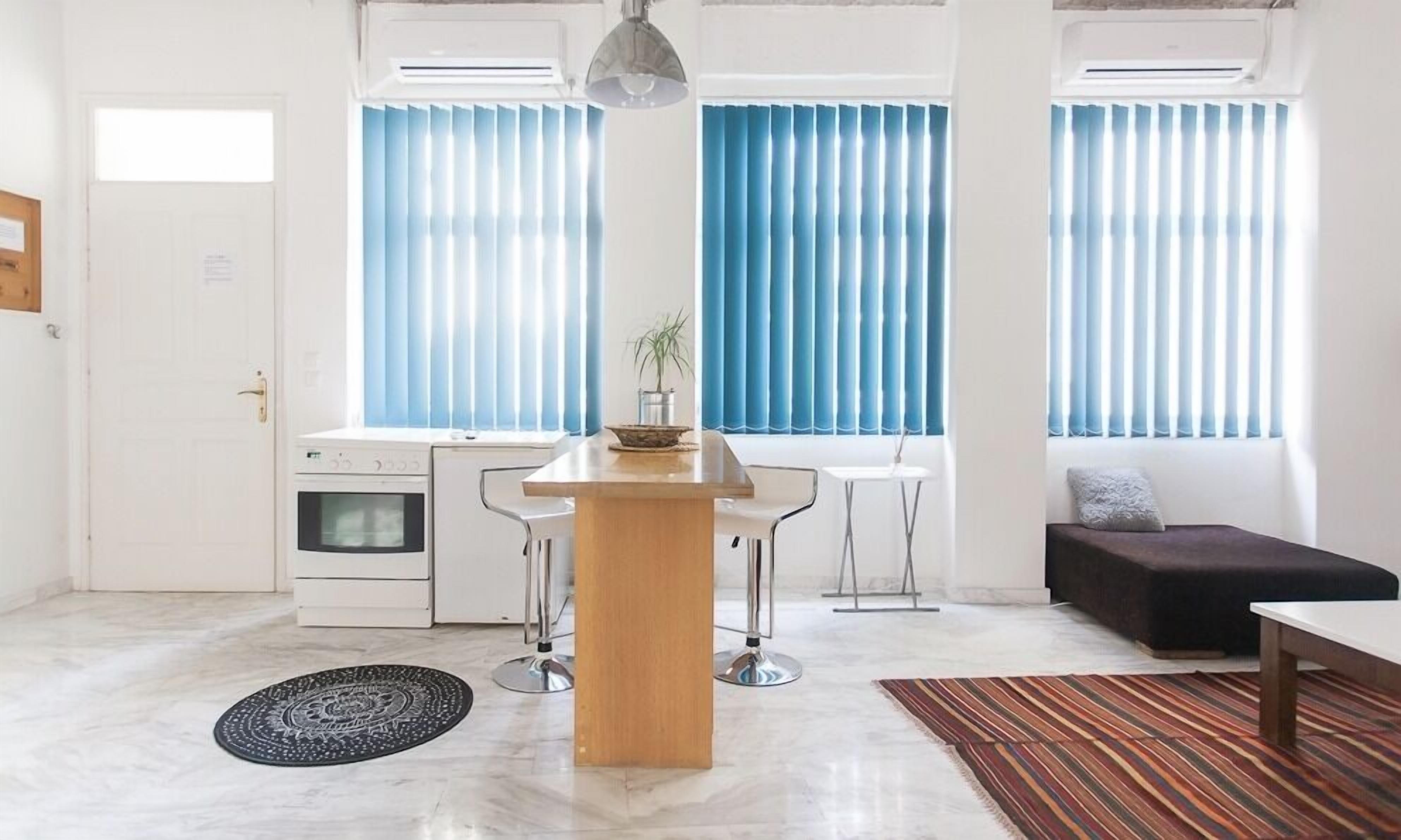 A modern kitchen with white cabinets, a built-in oven, and a dining area with a wooden table and bar stools.