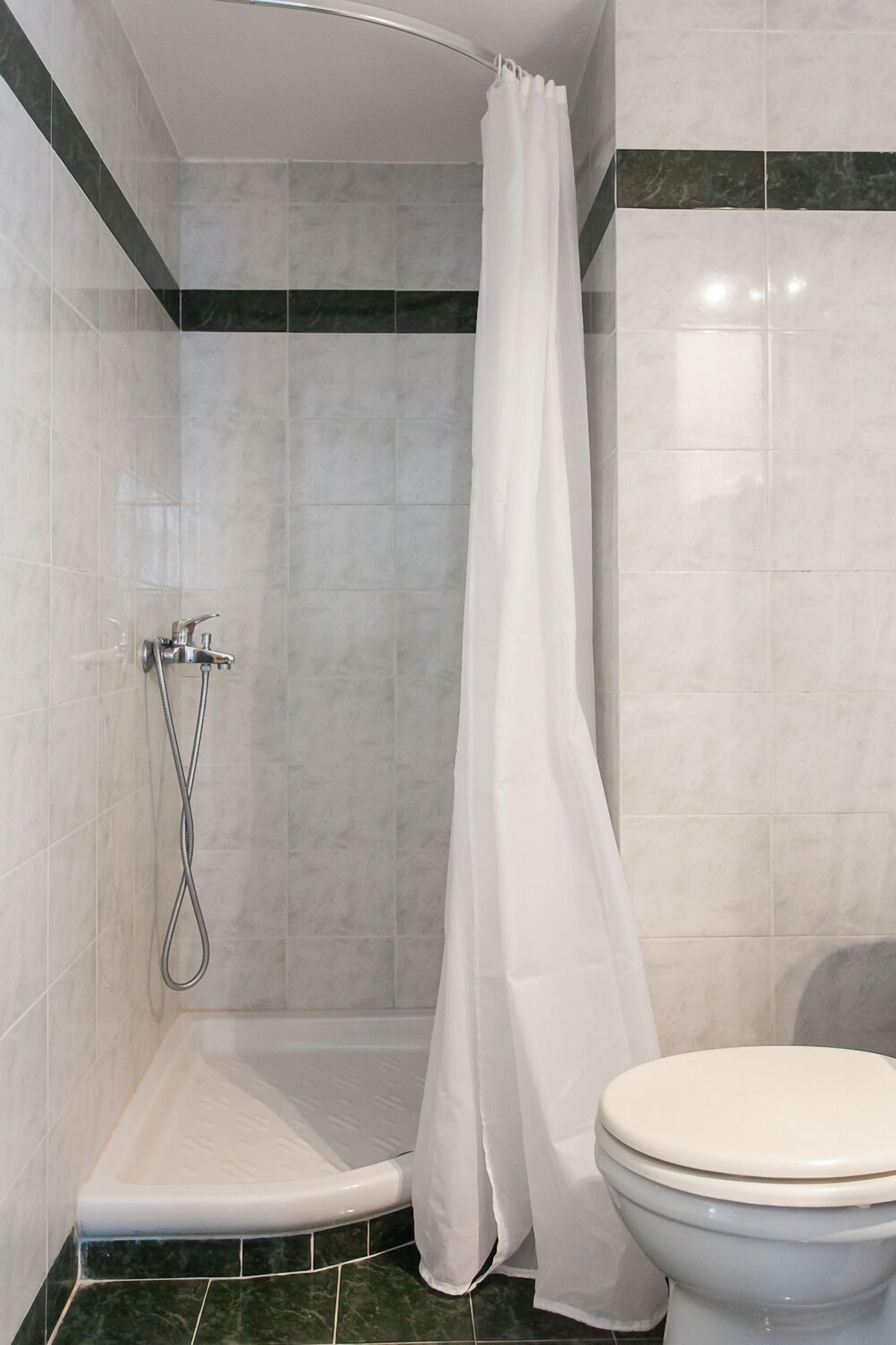 Une salle de bain avec douche, toilettes et murs carrelés.