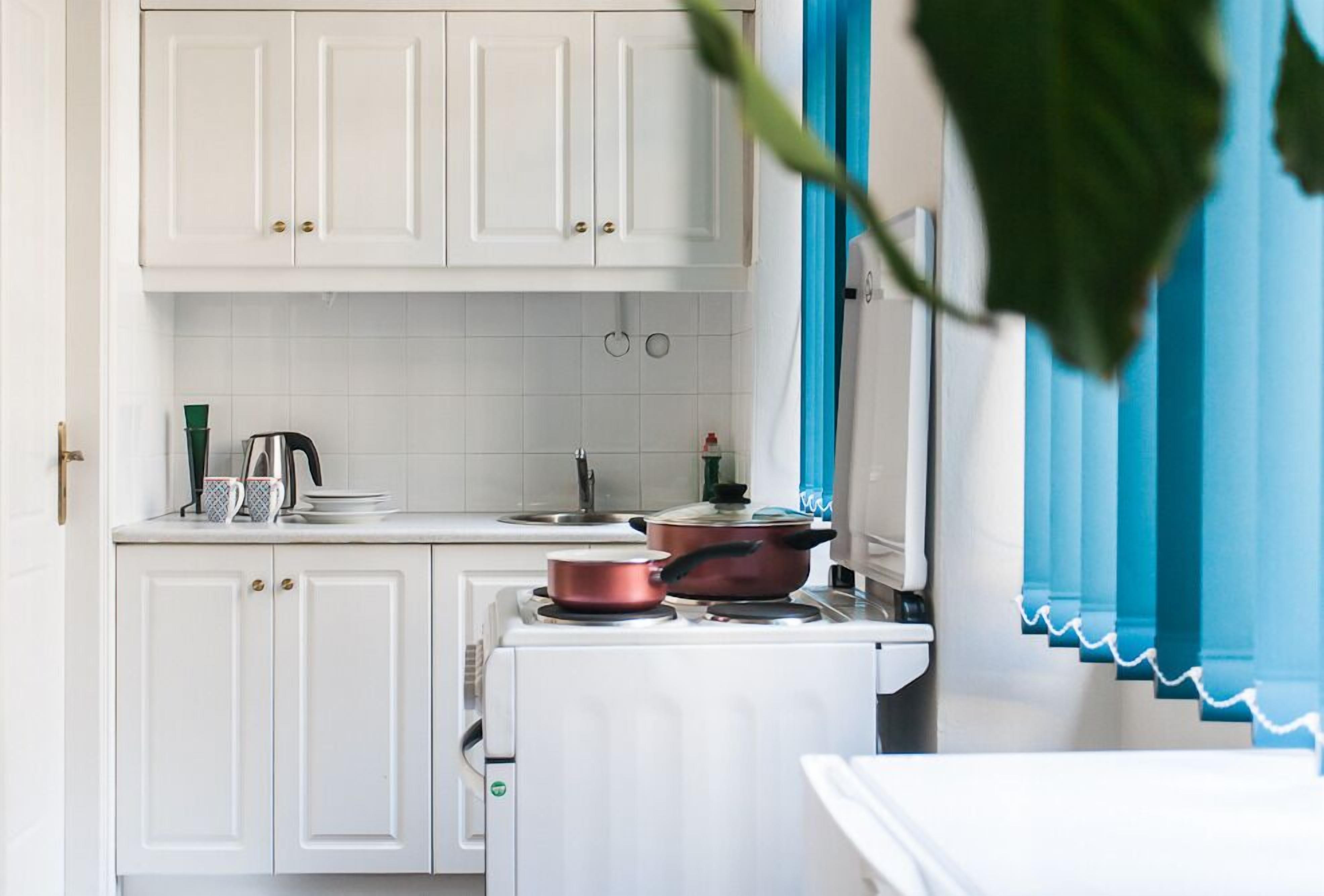 A kitchen with white cabinets, a stove, and a pot on the counter.