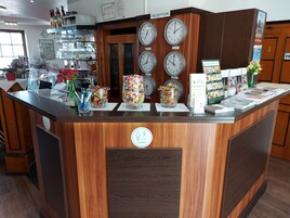 Una reception con orologi, un contenitore di vetro con caramelle e una bacheca con il menu.