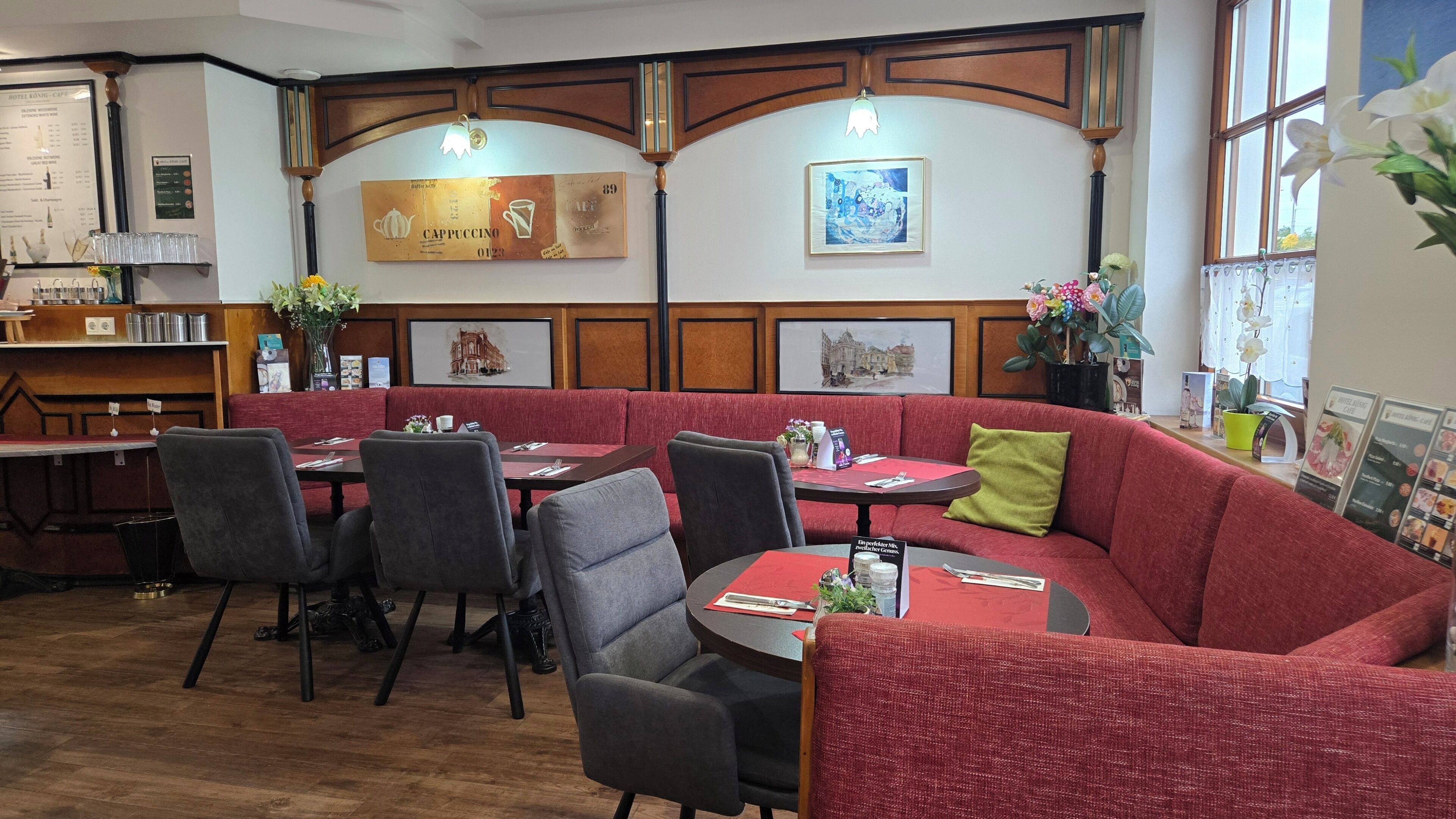 A restaurant with red upholstered booths, wooden paneling, and framed artwork on the walls.