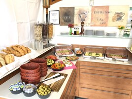 Un buffet con diverse pietanze, tra cui pasticceria, frutta e salumi.