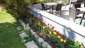 A garden with a row of tulips, a stone border, and outdoor furniture. - Landhotel Krone (Oberreute)