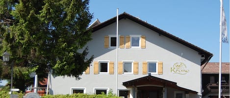 A two-story building with a sign reading "Krone" and a welcoming sign for bikers.