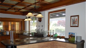 A modern kitchen with a wooden island, stainless steel appliances, and a large window offering a view of the outdoors. - Landhotel Krone (Oberreute)