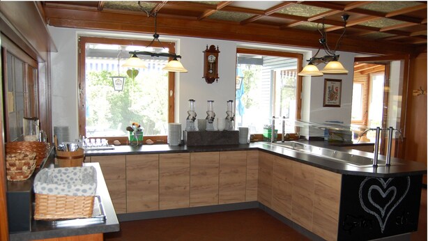 A kitchen with wooden cabinets, a sink, and a clock on the wall. - Landhotel Krone (Oberreute)