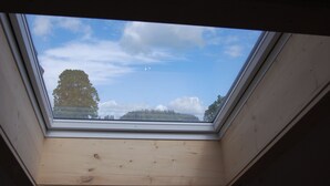 A skylight with a view of a tree and a forested hill. - Landhotel Krone (Oberreute)