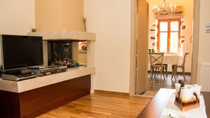 A modern kitchen with a built-in TV, a fireplace, and a dining area with a table and chairs. - Villa Vlatos (Kissamos)