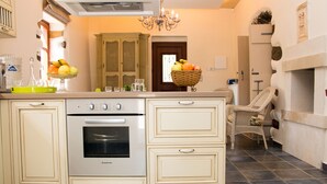A kitchen with a built-in oven, a sink, and a dining area with a wicker chair. - Villa Vlatos (Kissamos)