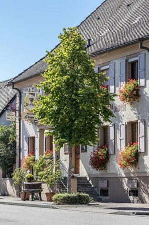 A building with a traditional facade, a staircase leading to the entrance, and flower boxes on the windows. - Gasthof Löwen (Breisach)