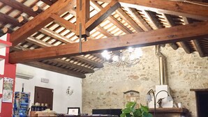 Ein rustikales Interieur mit freiliegenden Holzbalken, einer Steinwand, einer Bar und einem Blumentopf.