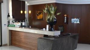 A reception desk with a modern design, featuring a wooden slatted backdrop, a black marble counter, and a vase with white flowers. - Danai Hotel & Spa (Katerini)