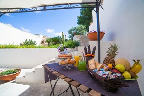 A table with food and drinks, surrounded by potted plants and a clear sky. - Bianco Sale Trapani (Misiliscemi)