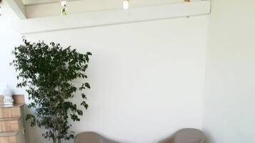 A patio area with a round table, two armchairs, and a potted plant.
