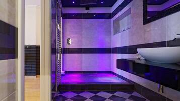 Bathroom features a geometric checkered floor, gray and black tile walls, and a sleek white sink with a black countertop.