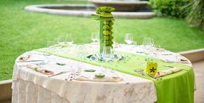 Une table ronde dressée pour un repas, avec une nappe verte, une nappe blanche et un centre de table décoratif.