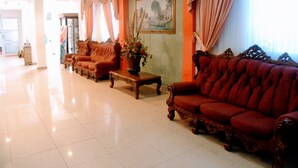 A spacious lobby with a red sofa, a wooden coffee table, and a painting on the wall. - Hotel Meryland (Colon)