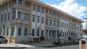 A large, multi-story hotel with a beige facade, multiple balconies, and a stone base. - Hotel Meryland (Colon)
