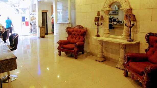 A lobby with two red upholstered chairs, a marble fireplace, and a chandelier. - Hotel Meryland (Colon)