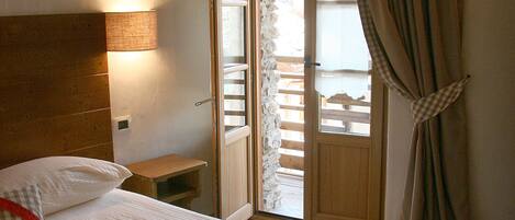 A bedroom with a bed, a nightstand, a lamp, and a window with curtains.