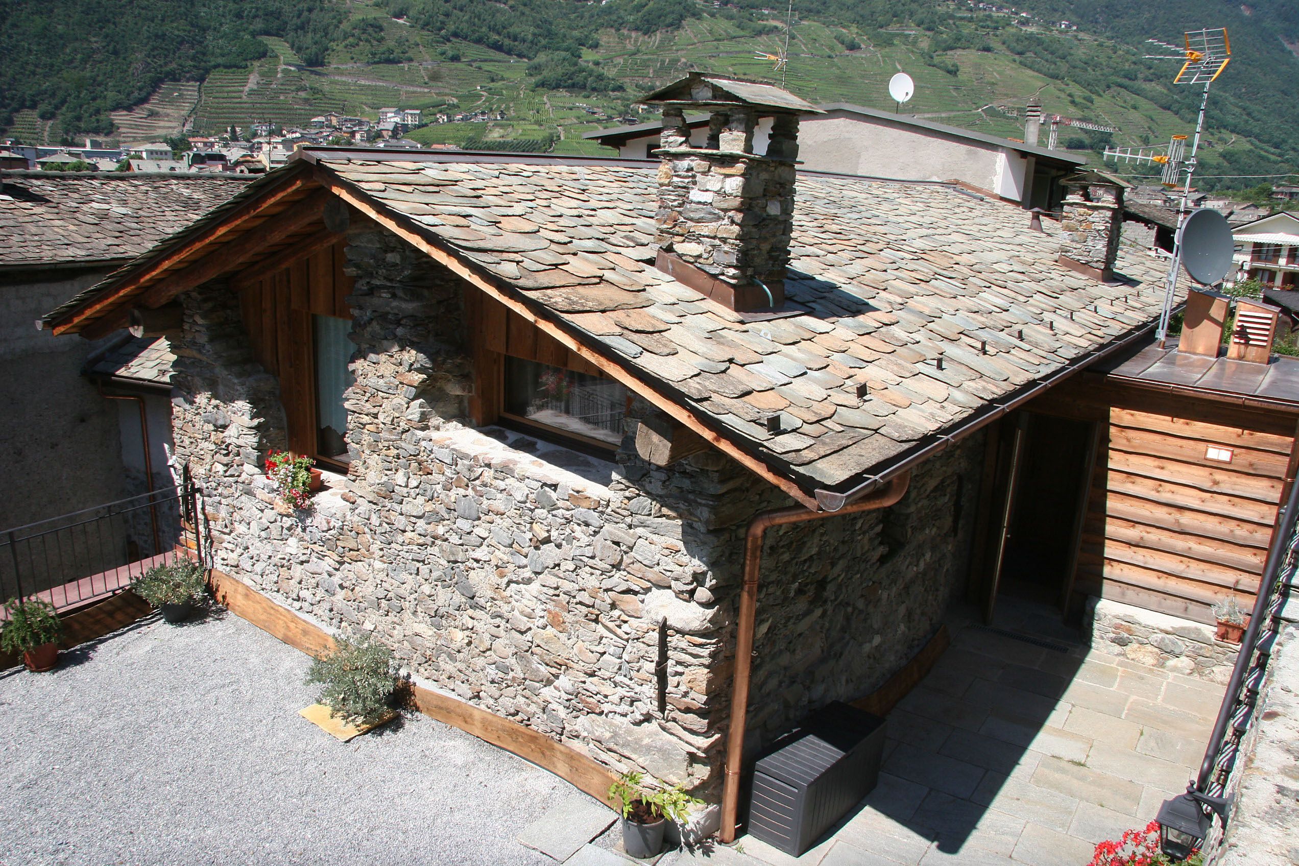 Un bâtiment rustique en pierre, doté d’un toit en pente, de poutres en bois et d’une cheminée.
