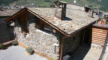 Un bâtiment rustique en pierre, doté d’un toit en pente, de poutres en bois et d’une cheminée.