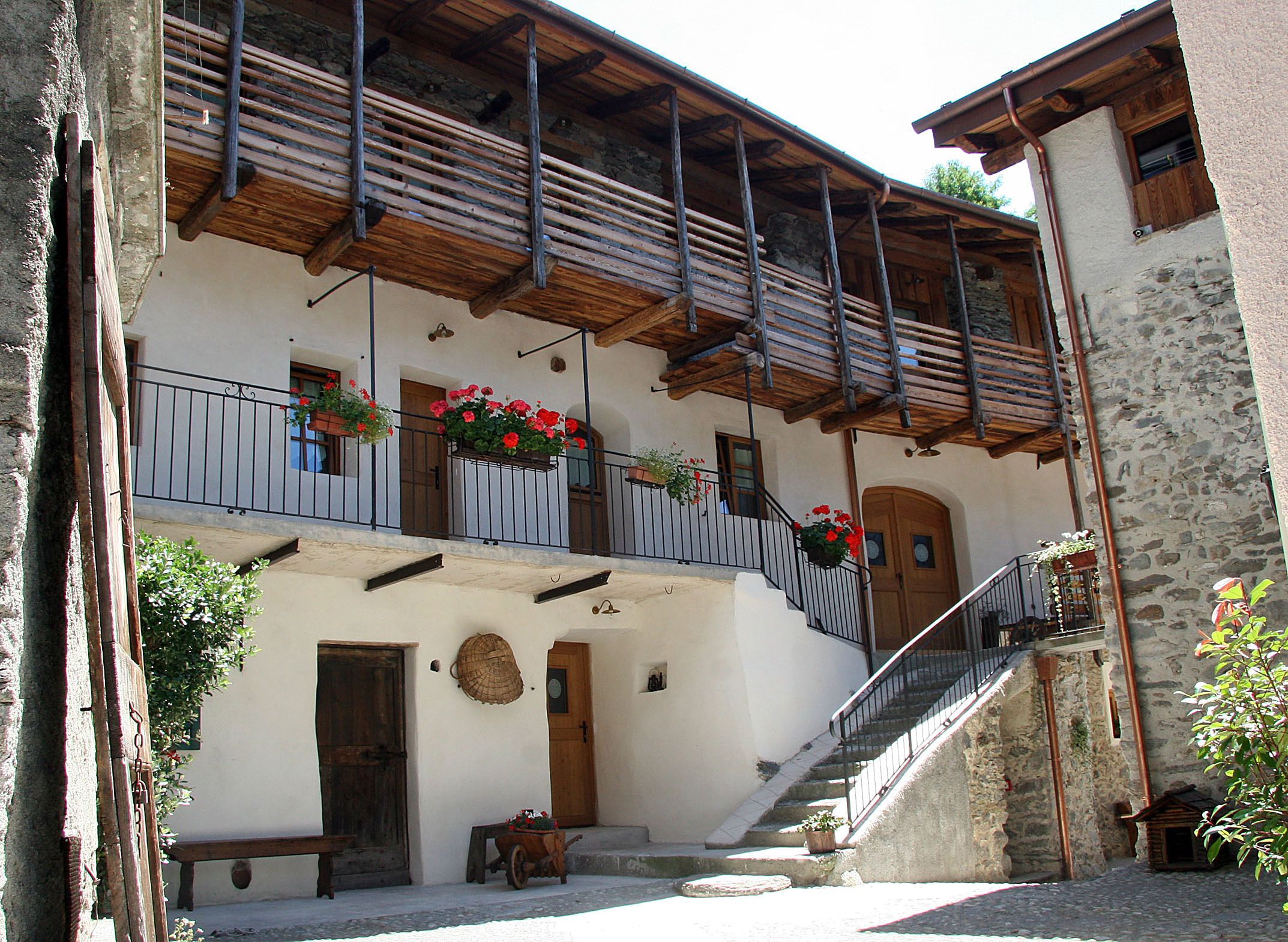 Ein traditionelles Gebäude mit einem hölzernen Balkon, einer Steinmauer und einer Holztreppe zum Eingang.