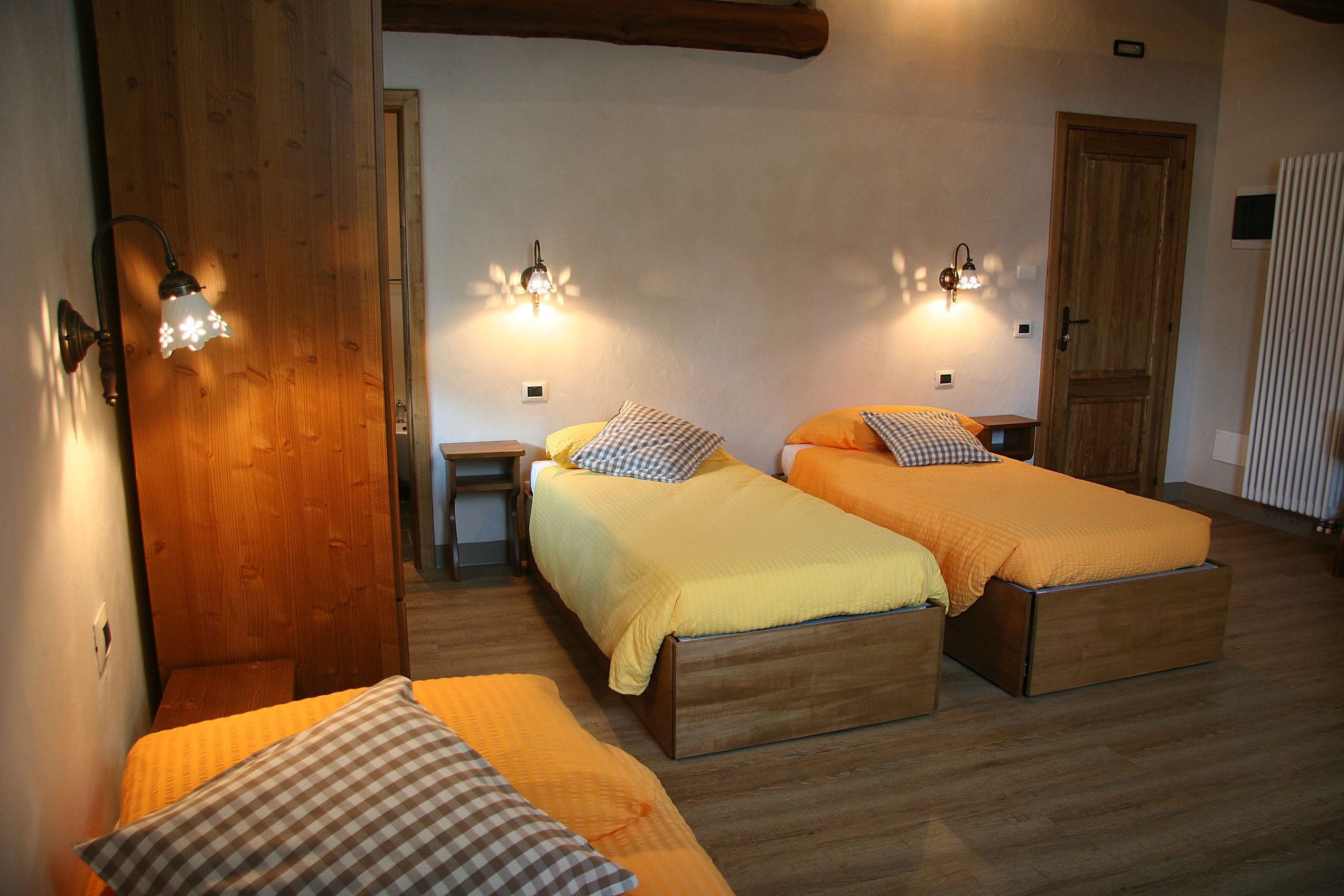 Ein Zimmer mit zwei Betten, Holzboden und Wandleuchten.