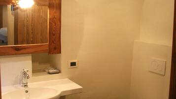 Ein Badezimmer mit einem weißen Waschbecken, einem Holzschrank und einer Toilette.