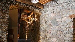 Un pasillo de paredes de piedra con vigas de madera y un candelabro colgante.