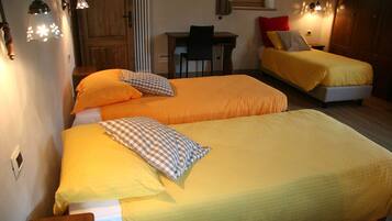 Una habitación con dos camas, cada una con ropa de cama amarilla y almohadas a cuadros. Hay un escritorio con una silla y una ventana con cortinas.