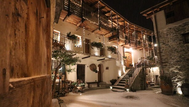 Un edificio tradicional con fachada de piedra, balcones de madera y una escalera que conduce a un nivel superior.