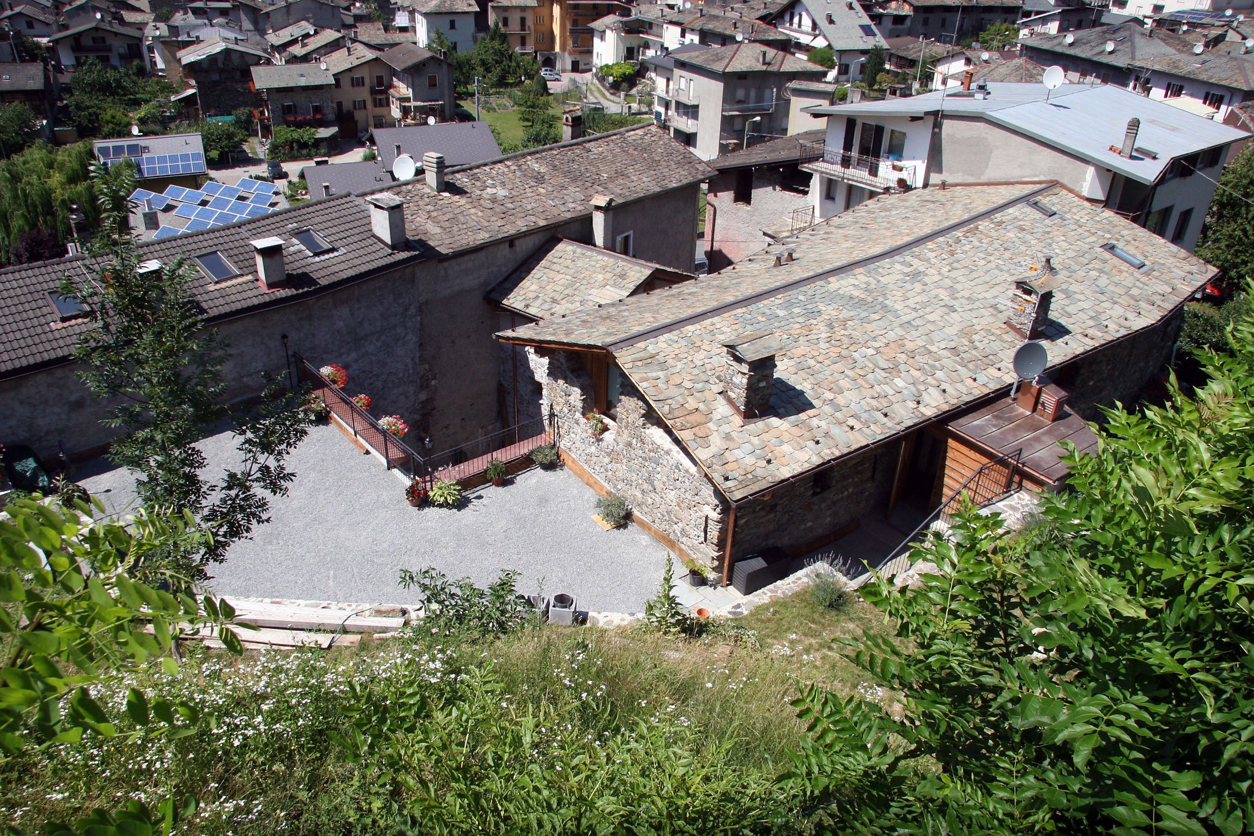 Un barrio residencial con edificios de piedra, un patio empedrado y paneles solares en los tejados.