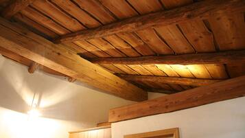 Ein Zimmer mit sichtbaren Holzbalken und schrägverdeckter Decke.