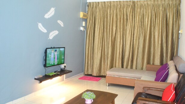 Una sala de estar con una televisión de pantalla plana, un sofá, una mesa de centro y una cortina.
