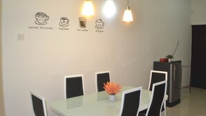 Un comedor con una mesa, sillas e ilustraciones de tazas de café en una pared.
