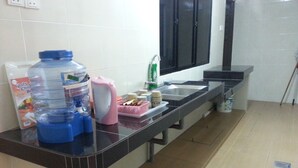 Una cocina con encimera negra, dispensador de agua, un recipiente rosa y un lavamanos.